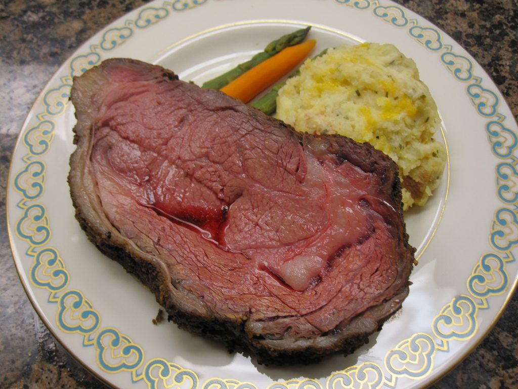 A slice of prime rib on a plat with side dishes